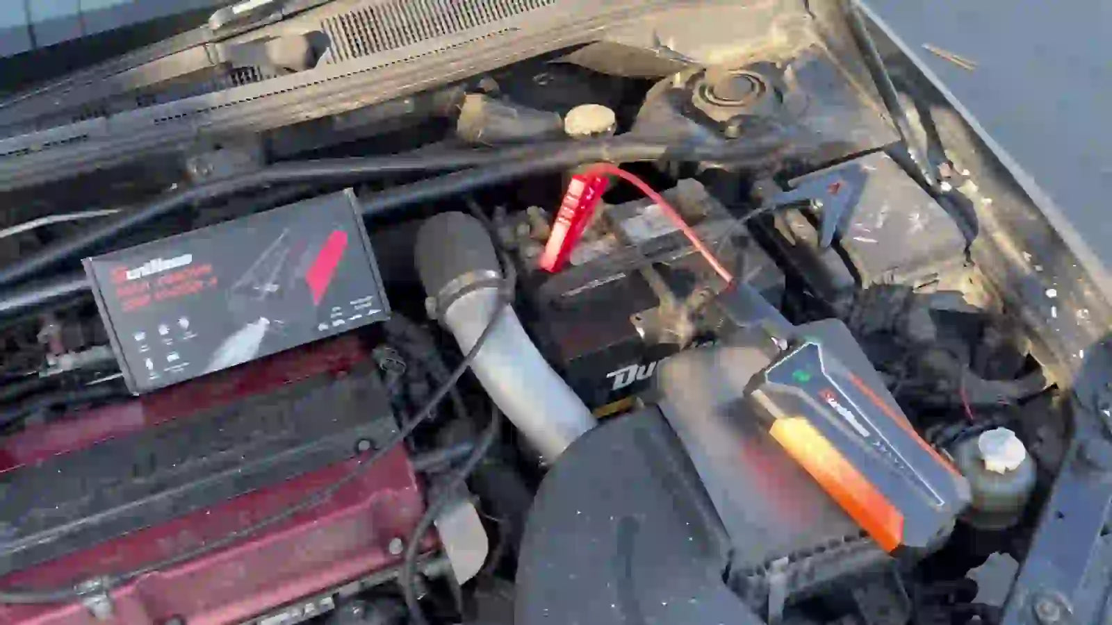 SuntNeew A20 jump starter connected to a car battery in an engine bay