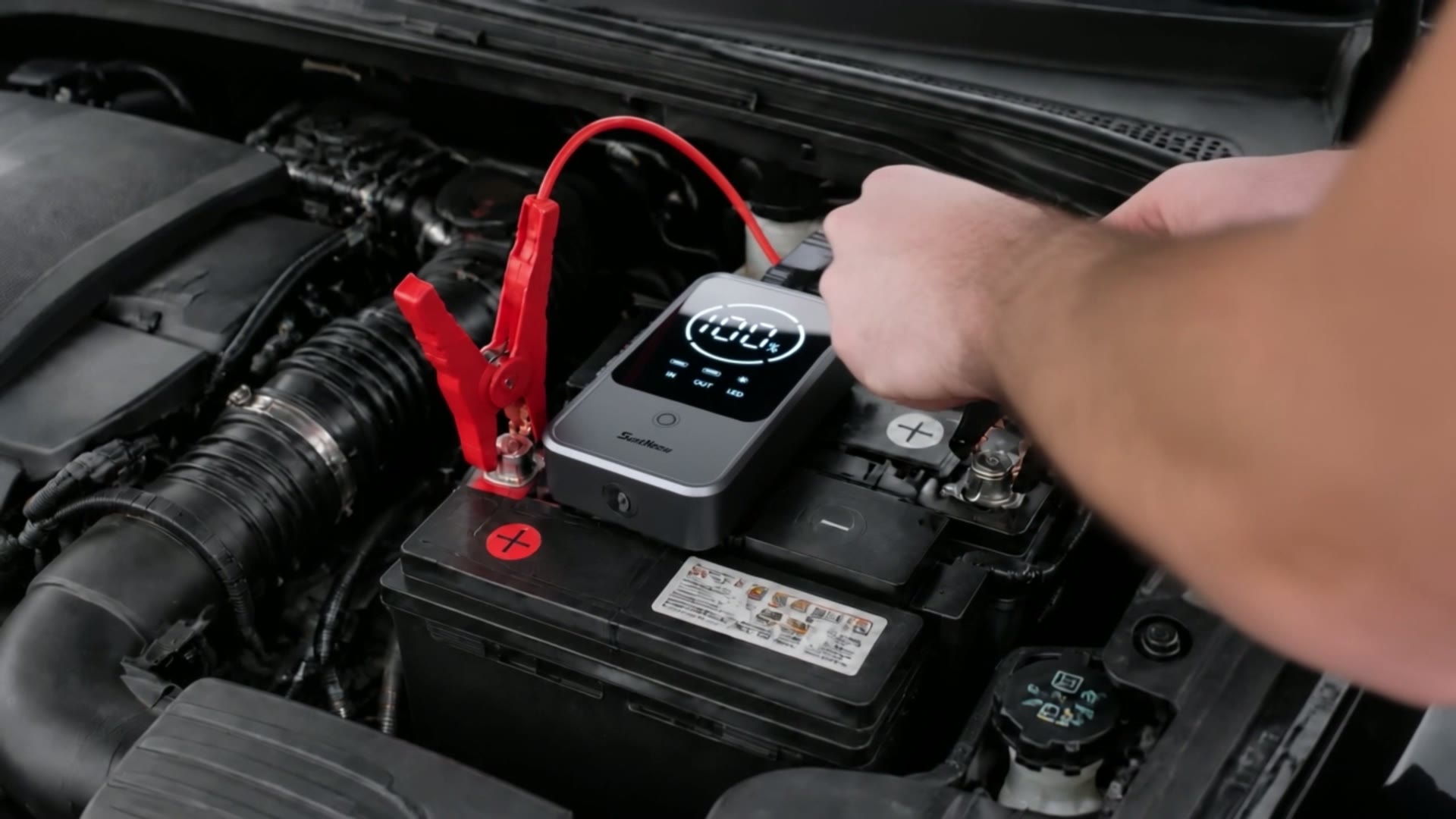 SuntNeew U32 jump starter with smart clamps connected to a car battery